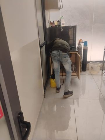 Technician treating the base of a cabinet and wall junction during a scheduled treatment