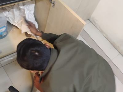 Close view of a technician directing spray into the gap beneath a sink unit